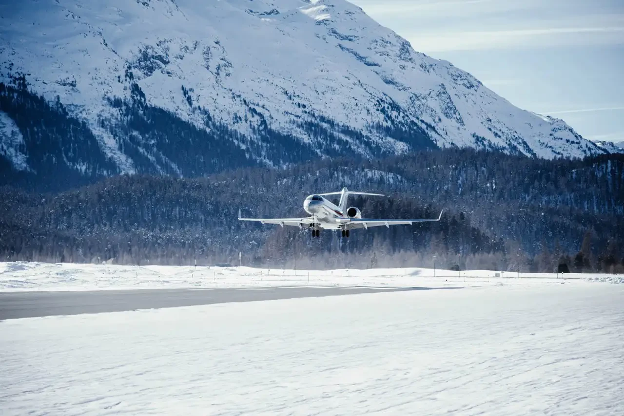 A VistaJet plane landing on a runway in a snowy environment.